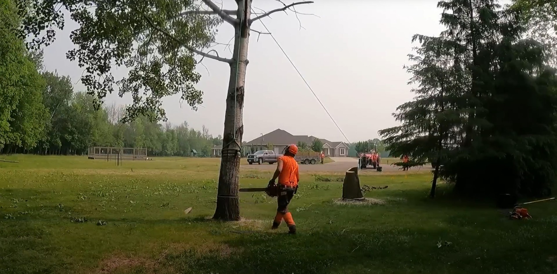 Emergency tree removal service with professional arborist cutting fallen tree in residential area